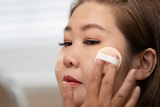 Focused on her makeup skills, a woman applies foundation with precision, emphasizing her artistry in beauty application and creating a flawless look.