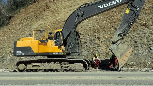 Budva, Montenegro - April 10, 2025: repair of the Budva - Tivat road. Workers rest near the excavator. High quality photos