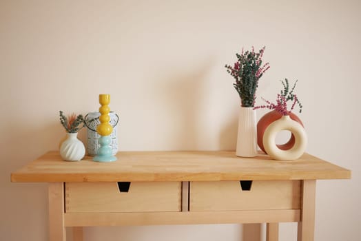 Wooden table displays colorful vases holding fresh flowers in a cozy space.
