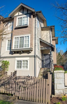 Residential townhouse entrance with wooden fence in front on early sprint day in Vancouver, Canada