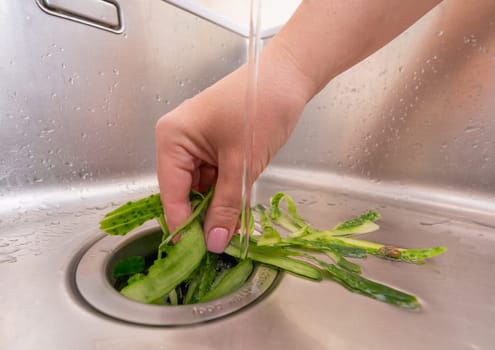 Food waste management: cucumber peels being processed in a garbage disposal.
