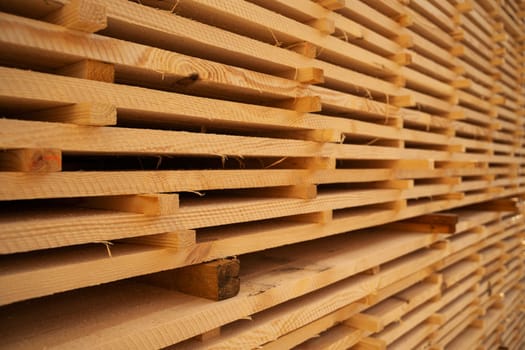 Close up stacks with wooden planks in sawmill storage warehouse. Stack of wood planks for construction in warehouse