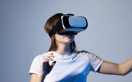 Young brunette woman girl in white t-shirt is using VR helmet. Virtual reality, technology, innovation concept