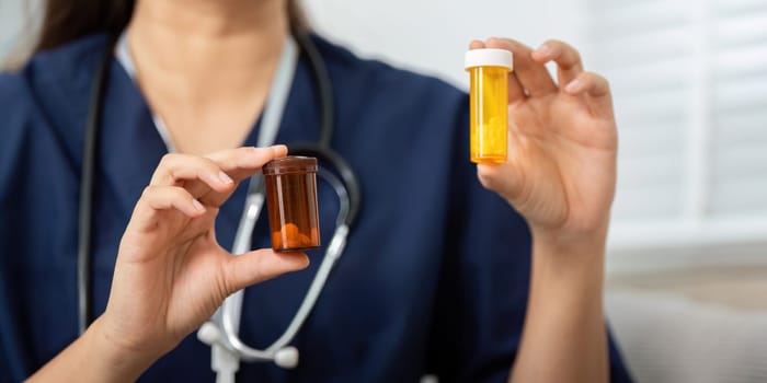 A caregiver holds two medication bottles, actively explaining their purposes to an elderly patient, ensuring clarity and promoting effective health management.