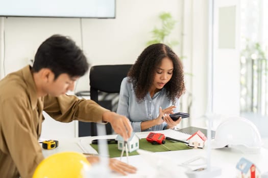 In this image, two colleagues engage in a dynamic conversation, examining sustainable housing models and discussing their effectiveness in modern living.