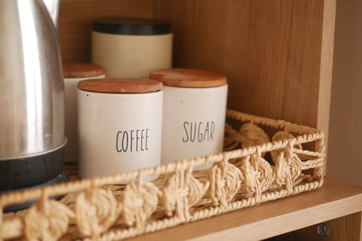 Containers labeled coffee and sugar sit on a rustic wooden shelf in a kitchen.
