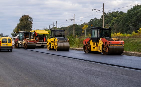 Heavy Asphalt Road Roller with Heavy Vibration Roller Compactor and Asphalt Pavers laying new asphalt on the roadway on a road construction site