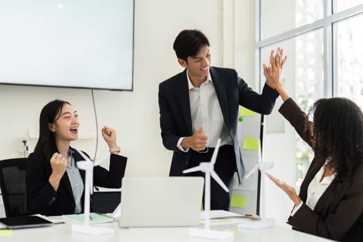 A moment of celebration in a professional setting as team members high-five each other after successfully implementing an ESG initiative, showcasing teamwork and achievement.
