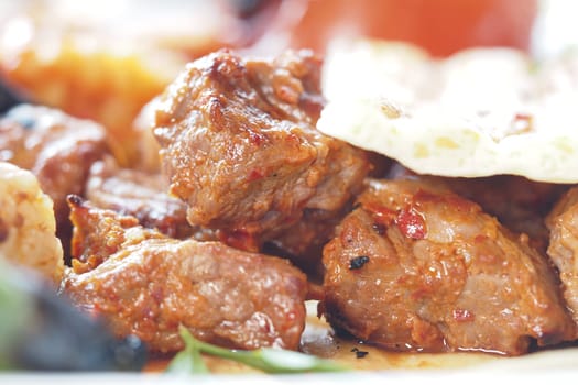 Tender grilled meat is served on a plate with garnishes outdoors.