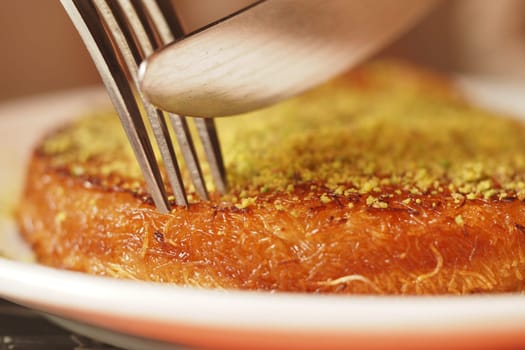 Golden Kunafa Dessert Topped with Pistachios and Served on a Plate