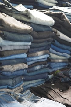 Multiple stacks of various denim jeans organized by color and style.