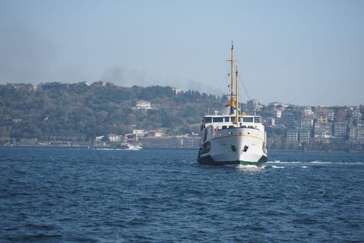 A ferry sails through the blue waters of Istanbul, surrounded by hills.