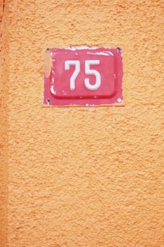 House number 75 is prominently displayed on the bright orange wall.
