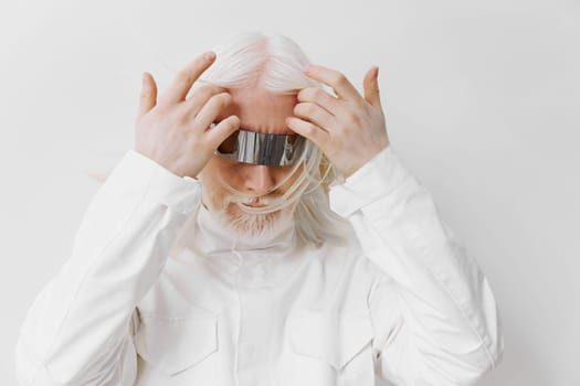 A unique portrayal of an individual with long white hair dressed in a modern, all white outfit and wearing innovative metallic headgear The quiet white background enhances the futuristic vibe, making the subject stand out as a symbol of advanced technology and creativity