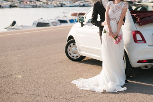Elegant wedding couple holding a beautiful bouquet of pink roses.