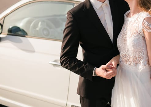 The bride and groom hold hands on their wedding day ir in love on a sunny day.