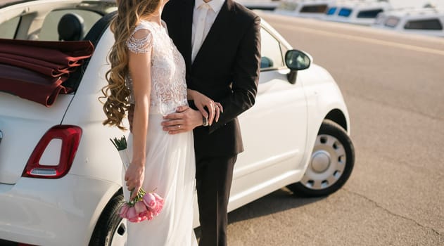 Elegant wedding couple holding a beautiful bouquet of pink roses.