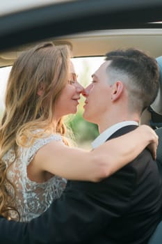 Couple about to kiss in a romantic embrace inside a car. Love, intimacy, connection and emotional closeness captured in a candid moment in wedding day.