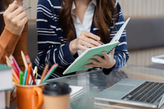 In a cafe, one student shares valuable insights as she writes in her notebook, highlighting the collaborative spirit of learning and friendship.
