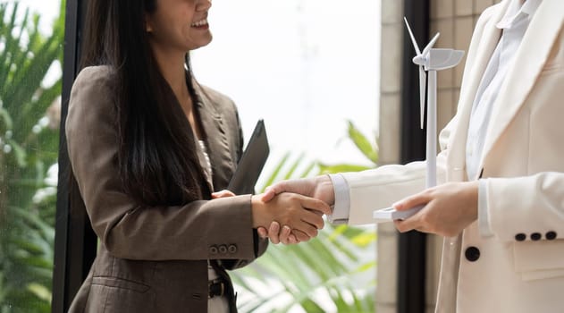 A moment of agreement as two women in business attire shake hands, signaling a partnership focused on environmental sustainability and innovative solutions.