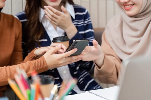 The group of friends shares a light hearted moment while looking at a smartphone, enhancing their connection and interaction in a cafe setting.