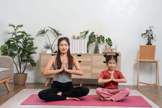 A peaceful interaction between a mother and daughter during their yoga session, both practicing mindfulness and cultivating inner peace in a nurturing environment.