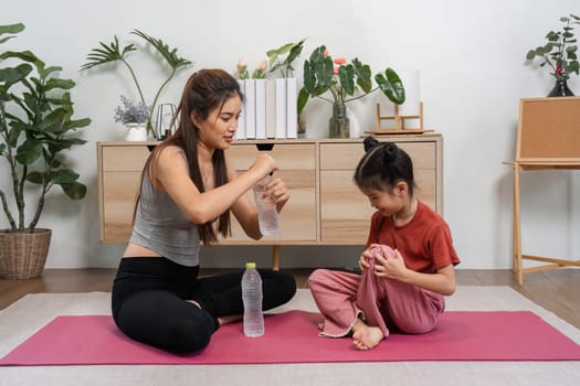 A dedicated woman shows a young girl the significance of hydration during their exercise session, fostering a love for fitness and healthy habits.