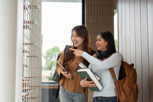 Excited students pointing at a notice board while discussing upcoming events, embodying the spirit of university life and social connections.
