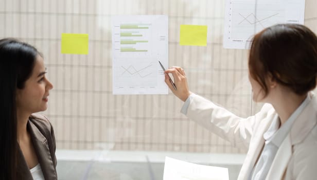 In a modern office, a woman points out key findings in ESG data, while her colleague observes, emphasizing the importance of informed decision-making in sustainability.