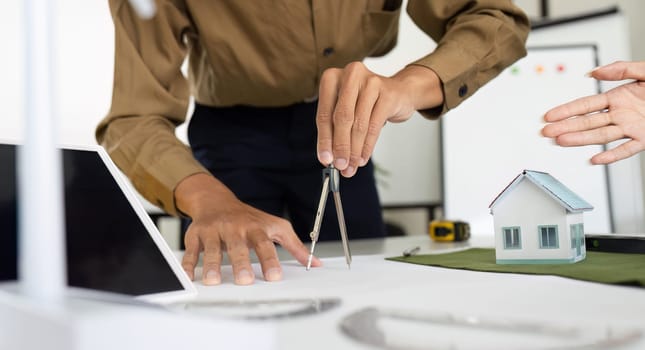 A pair of professionals utilize drafting tools to create eco-friendly building designs, emphasizing precision in sustainable architecture.