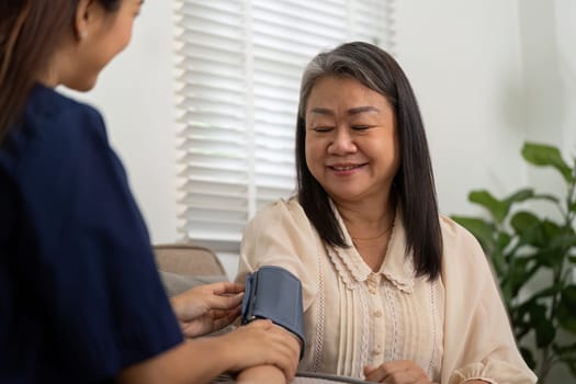 An attentive caregiver measures the blood pressure of an elderly woman, ensuring her health is monitored with care and precision.