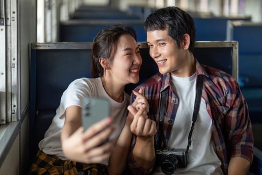 Inside a train, a couple takes a selfie, their smiles radiating happiness. The moment encapsulates the joy of shared experiences while traveling.