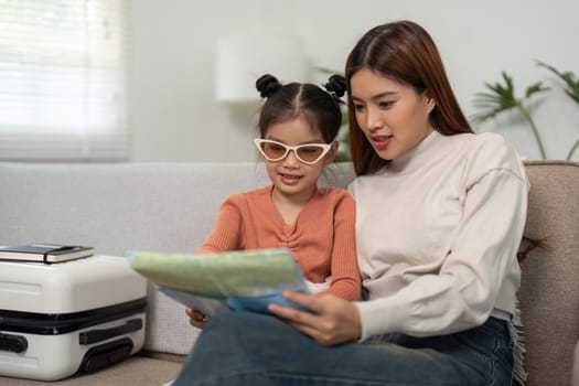 As they get ready for an exciting trip, the mother and daughter share a moment of exploration over a map, discussing potential destinations to visit.