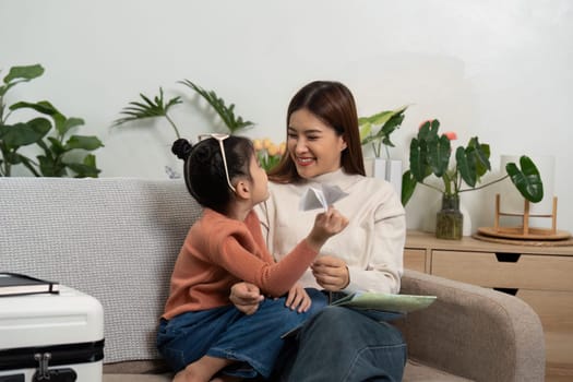 Captured in a cheerful moment, a mother and daughter engage in planning their travel adventure, embracing creativity and joy.