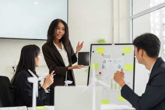 In a modern office environment, a confident presenter shares effective ESG strategies with her team, emphasizing sustainability and corporate responsibility during a meeting.