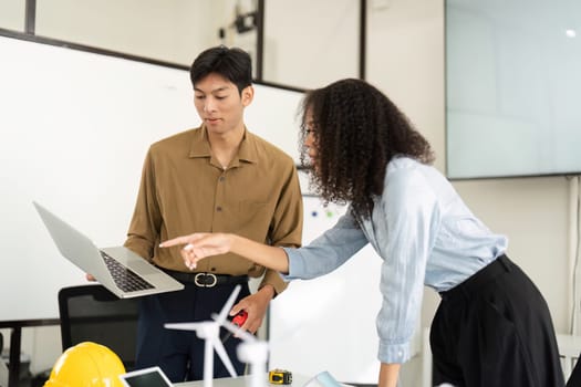 A focused discussion about sustainable energy solutions unfolds as two professionals interact with models and technology, fostering innovative ideas.