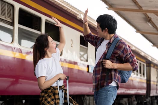 At the train station, a couple shares an enthusiastic high-five, showcasing their excitement about the adventures that await them on their trip.