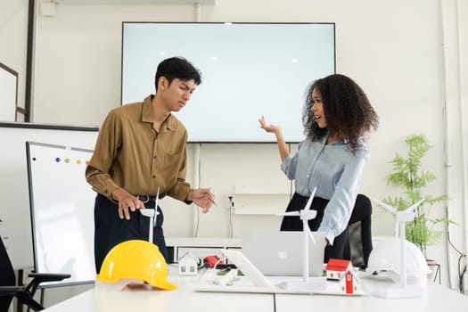 Two colleagues engage in a lively discussion on renewable energy solutions for their upcoming sustainable projects in a creative workspace.