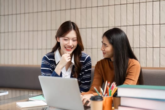 Two university students share ideas and discuss notes while studying together at a cozy cafe table. Their camaraderie enhances their learning experience.