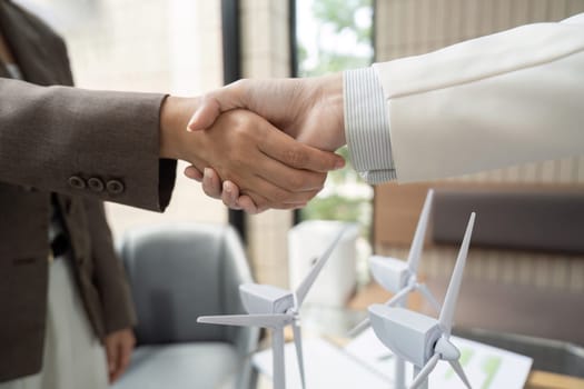 Two business partners engage in a handshake to solidify their commitment to sustainable projects, promoting environmental responsibility and collaboration in the workplace.