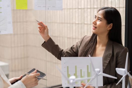 In a modern office, a woman presents sustainability data related to renewable energy, highlighting the importance of ESG metrics in decision-making.