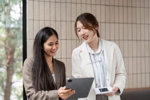 Two women engage in a discussion about renewable energy solutions, utilizing technology for better sustainable strategies.