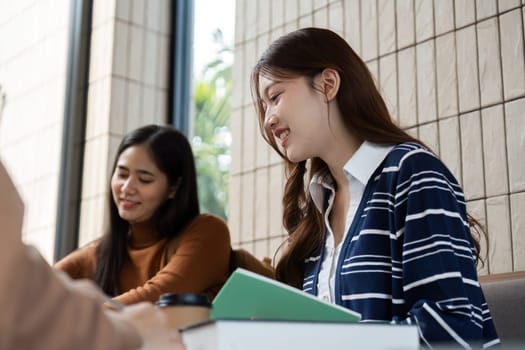 A lively study group atmosphere unfolds as three friends collaboratively go over schoolwork, sharing insights and laughter amidst their studies over coffee.