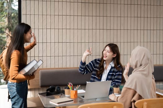 One student enters the cafe, greeting her friends who are busy studying. A moment of connection and warmth as they transition between discussion and socializing.