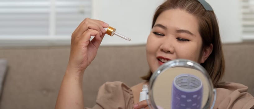 A delighted woman holds a skincare serum dropper, eagerly preparing to nourish her skin, highlighting the synergy between beauty products and self-confidence.