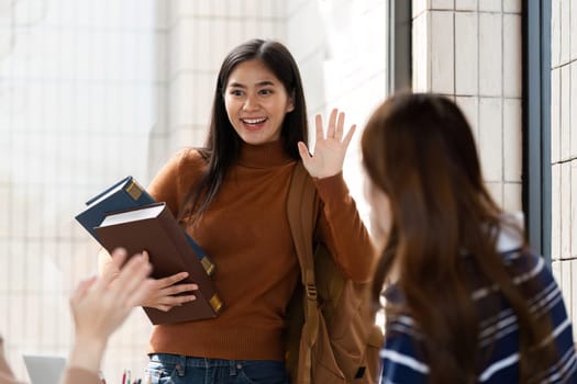 With books in hand, a student waves joyfully at her friends, expressing a sense of excitement and camaraderie in a lively setting.