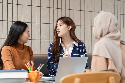 A group of students collaborates on their school projects at a cafe, sharing ideas and notes. Their interaction symbolizes teamwork and knowledge sharing in an educational setting.