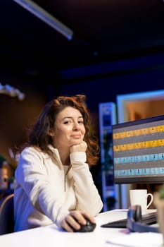 Portrait of happy photo editor color correcting photographs in creative studio while enjoying cup of coffee. Smiling photographer selecting best pictures for editorial content