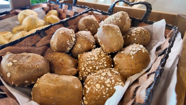 Whole grain rolls topped with oats are arranged in a woven basket.