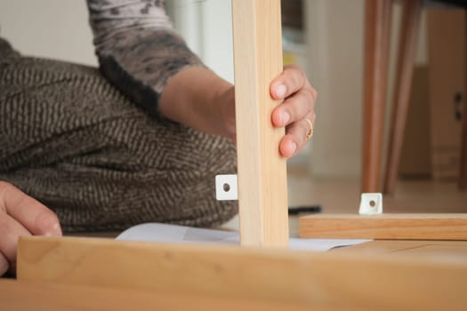 A person is carefully connecting wooden pieces for furniture assembly.